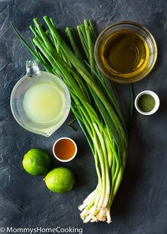 green onions, lemons, and other ingredients on a black surface with a gray background