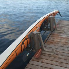 an orange and white boat sitting on top of a wooden dock next to the water