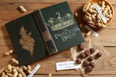 the princess bride book is surrounded by nuts and chocolates on a wooden table with a bowl of peanuts next to it