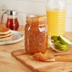 a wooden cutting board topped with a jar of pickles