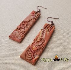 two brown earrings with intricate designs on them