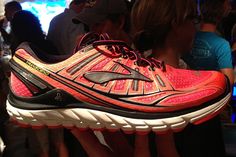 a pair of running shoes on display in a crowded room with people looking at them