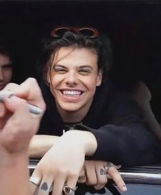 a woman with her hands on the door of a car smiling and pointing at something