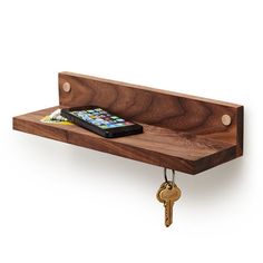 a wooden shelf with a cell phone on it and two keys hanging from the hooks