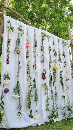 a white sheet with flowers hanging from it's sides in front of some trees