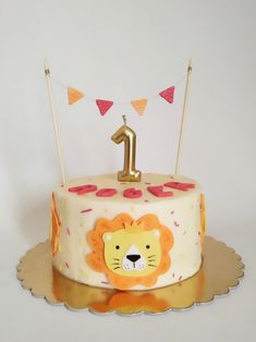 a first birthday cake with a lion face and number one on the top, sitting on a gold platter