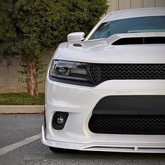 the front end of a white car parked in a parking lot