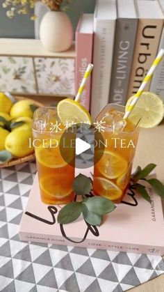 two glasses filled with iced lemon tea sitting on top of a table next to books