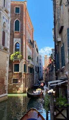 a boat is traveling down a narrow canal in an old city with tall buildings and green shutters on either side