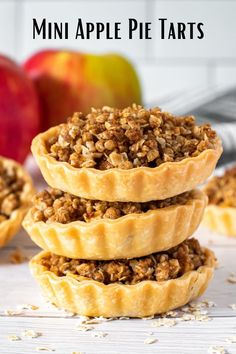 mini apple pie tarts stacked on top of each other with apples in the background