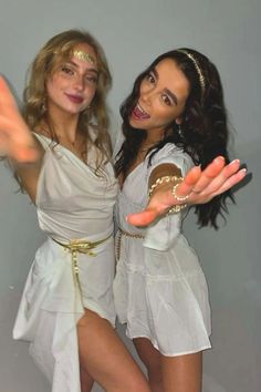 two women dressed in white posing for the camera with their hands out and one holding her hand out