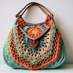 a crocheted purse is sitting on a table next to a white wall with a brown leather handle