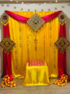 a yellow and red stage set up for a wedding ceremony with decorations on the floor