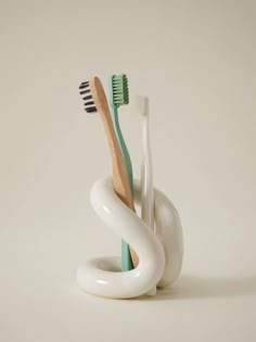 three toothbrushes sitting in a white holder