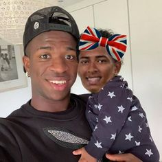 a man holding a baby in his arms with the british flag on it's head