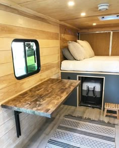 the interior of a tiny home with wood flooring and walls, including a bed