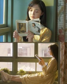 a woman sitting on a window sill reading a book