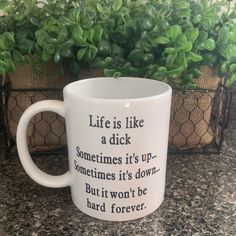 a white coffee mug sitting on top of a counter next to a potted plant