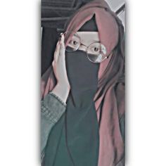 a woman wearing glasses and a hijab covering her face with a cell phone