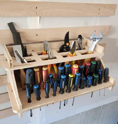 a bunch of tools that are sitting on a shelf in a workbench with pegs and pliers