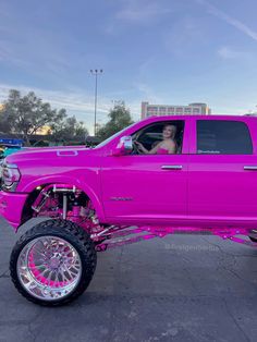 a bright pink truck is parked in a parking lot