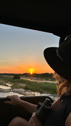 a woman sitting in the back seat of a car looking out at an open field