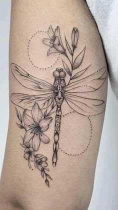 a woman's thigh with flowers and a dragonfly tattoo on the side of her leg