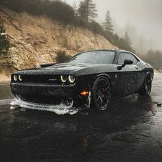 a black sports car driving down a wet road