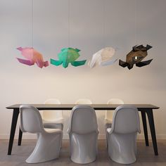 a dining room table with chairs and paper fish hanging from the ceiling