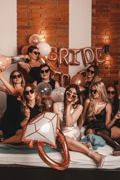 a group of women sitting on top of a bed in front of a brick wall