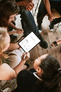 a group of people sitting around each other looking at an ipad