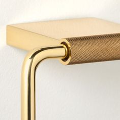 a close up of a gold colored metal handle on a white wall