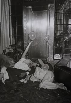 an old black and white photo of people in a room playing with bubbles on the floor