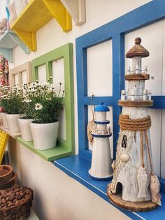 several different colored windows and pots with flowers in them on a shelf next to potted plants