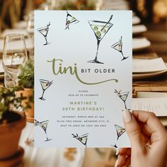 a person holding up a birthday card with martini glasses on it and the words tini older written in cursive writing