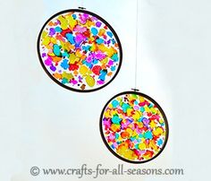 two colorful circles hanging from strings with confetti in the middle on white background