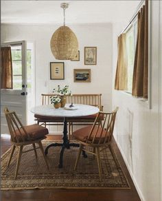 a dining room table with four chairs and a rug on the floor in front of it