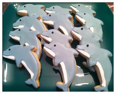 some cookies are shaped like dolphins on a green plate with white frosting and blue icing