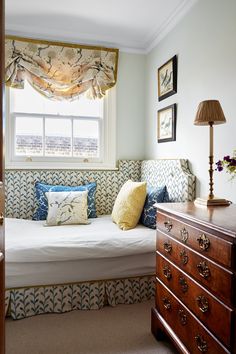 a bedroom with a bed, dresser and window in the corner next to an armoire