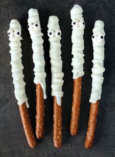 four halloween pretzels with googly eyes and white frosting on them are lined up in a row