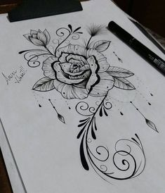 a drawing of a rose on top of a piece of paper next to a pen