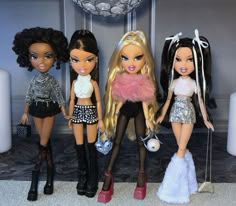 four dolls standing next to each other in front of a wall with chandelier