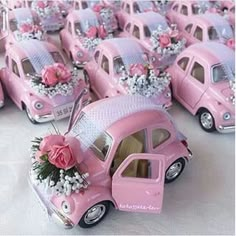 pink toy cars are lined up on the table with flowers in them and one car is painted pink