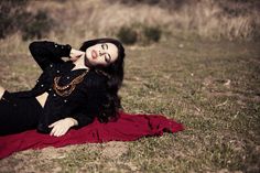 a woman laying on the ground in a black top and red skirt with her hands behind her head