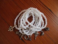 a white beaded necklace with charms on it sitting on a wooden table next to an earring