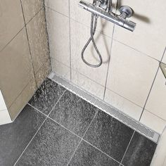 a shower head with water coming out of it's spout and the floor is tiled