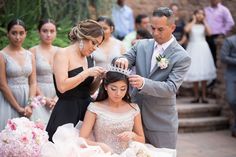 a bride and groom are getting ready to cut their hair at the wedding ceremony with other people in the background