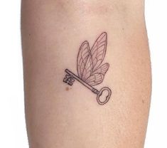 a small key and dragonfly tattoo on the leg