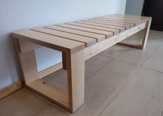 a wooden bench sitting on top of a tile floor next to a wall and window