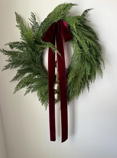 a christmas wreath hanging on the wall with a red ribbon